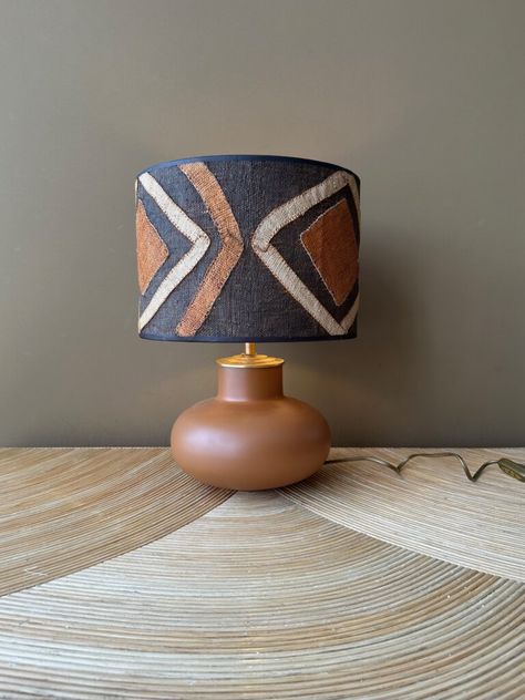 THIS EARTH TONED LAMP WITH AN AFRICAN KUBA SHADE WILL CREATE AN ECLECTIC TOUCH TO YOUR INTERIOR. African Interior Design, African Interior, Unique Table Lamps, Pottery Lamp, Wooden Log, African Art, Home Decor Styles, Light Shades, Earth Tones