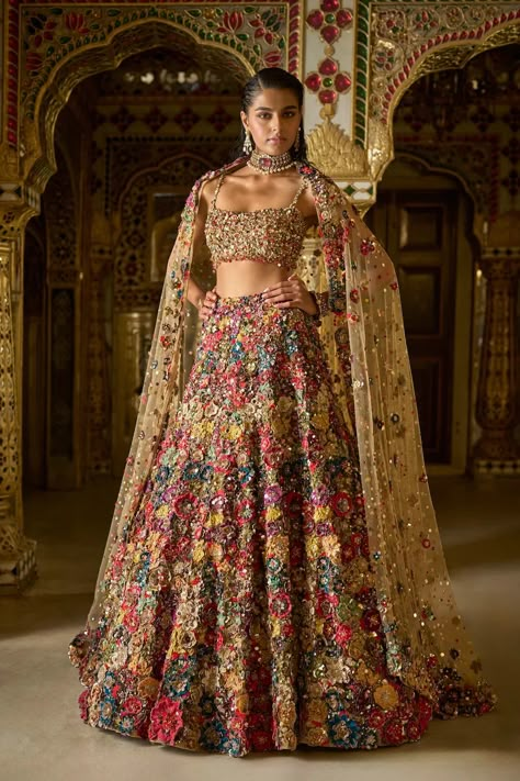 This lehenga set features heavily embroidered three-dimensional embroidery in a multitude of colours. The 3D flowers are further accentuated with crystal, bugle beads and platinum cut sequins. The strappy blouse is fully embroidered and shows delicate gold tassels at the waist. It is paired with the heavily embroidered dupatta having a matching border and floral motifs all over. From Seema Gujral's Palace of Dreams collection. DELIVERY TIMEPlease allow 8-12 weeks for your outfit to arrive. FABRIC DETAILSNet Professional cleaning only. Floral Wedding Lehenga, Summer Lengha, Indian Lehenga Aesthetic, Bridal Lengha Designs Latest, Sangeet Lehenga For Bride, New Indian Outfits, Sangeet Lehengas, Unique Indian Outfits, Prom Lehenga