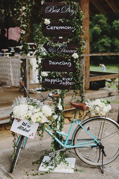 Directional signs adorned with cascading greenery pair with a vintage bike for a rustic look that borders on whimsy. Bike Wedding Decor, Bicycle With Flowers, Bicycle Wedding, Bike Wedding, Blue Bicycle, Corner Decoration, Rustic Wedding Decorations, Rustic Luxe, Wedding Props