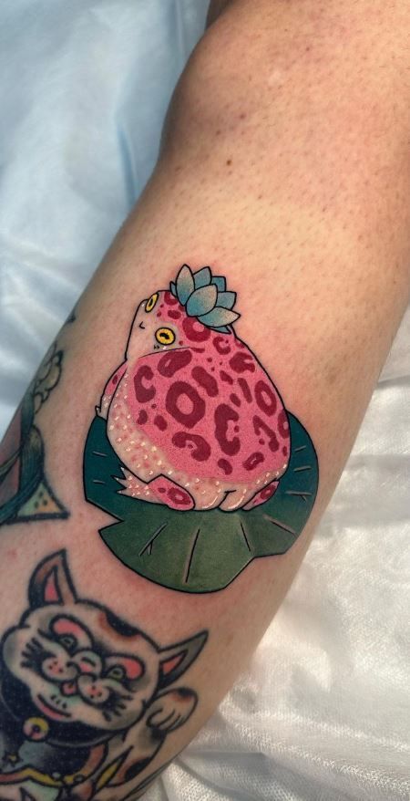 Frog tat Frog Tattoo Knee, Color Knee Tattoo, Floral Frog Tattoo, Halloween Frog Tattoo, Traditional Cute Tattoo, Witchy Frog Tattoo, Whimsical Tattoo Designs, Frog With Wings Tattoo, Narrow Tattoo Ideas