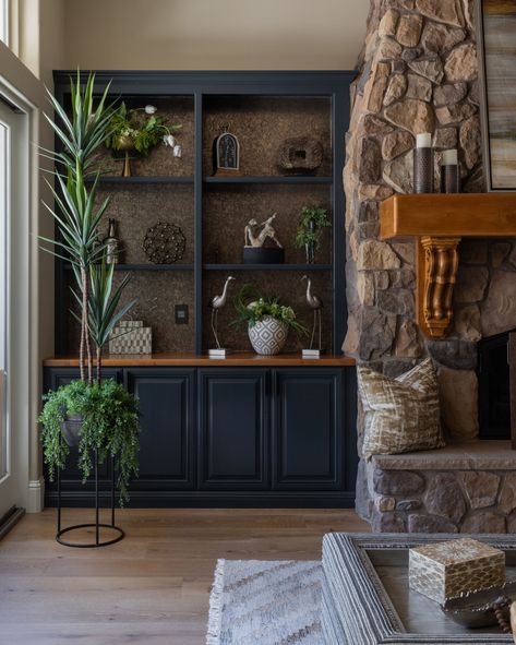 We've given this family room a stunning makeover, keeping the stone fireplace as the centerpiece. The bookshelves have been transformed with a depth-enhancing dark grey paint color, while the countertops retain their natural wood color to harmonize with fireplace & mantle. ✔️ An array of greenery and foliage brings nature indoors, creating a serene & calming atmosphere. #HomeRenovation #FamilyRoomMakeover #StoneFireplace #BookshelfGoals #NaturalWood #NewFloors #GraniteBayInteriorDesigner Dark Grey Stone Fireplace, Dark Wood Built Ins Around Fireplace, Stone Fireplace Dark Built Ins, Black Fireplace Wood Built Ins, Gray Stone Fireplace, Dark Gray Built In Bookshelves, Dark Stone Fireplace, Dark Wood Built In Bookshelves, Room Inspo Cozy