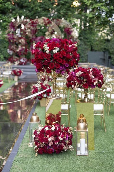 Impart natural freshness & vintage flair to your wedding aisle by incorporating majestic arrangements of red, white, & violet flowers in stunning gold vases. Place these lovely decorations atop shiny acrylic pedestal risers and on the floor for an enticing visual appeal. For an added whimsical effect, complement these bouquets by placing classy gold lanterns with white pillar candles on the floor. Wedding Aisle Decoration, Acrylic Pedestal, Decoration With Flowers, Event Decor Ideas, Party Decorations Table, White Violet, White Pillar Candles, Gold Lanterns, Violet Flowers