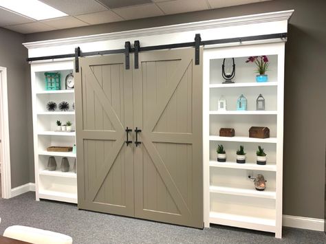 This custom bookcase built-in was designed with header detail & crown, shaker end panels, toe-kick, adjustable shelves, and two double-Z barn doors. Built In Shelves With Barn Doors, Built In Storage Wall With Barn Doors, Bookshelf With Barn Doors, Bookshelf Barn Door, Barn Door Bookshelf, Dining Room Built In, Scrapbook Room Organization, Custom Bookshelves, Built In Entertainment Center