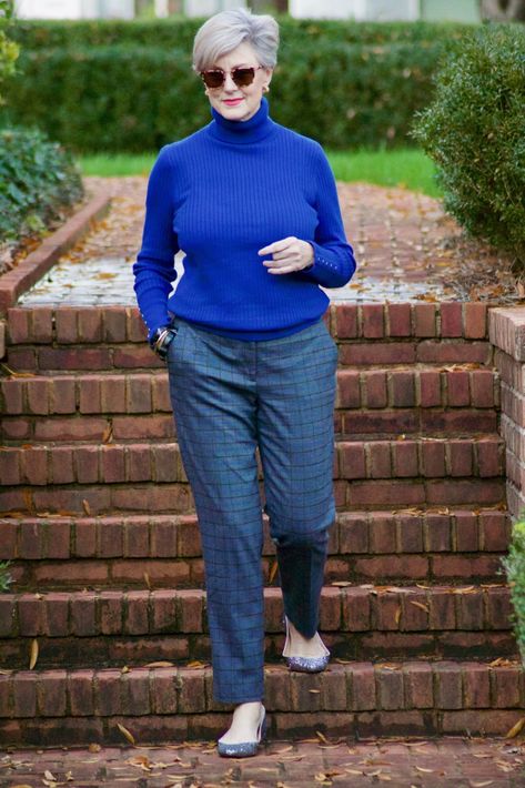 beth from style at a certain age wears plaid pants, cobalt blue turtleneck, green wool coat, blackwatch plaid cashmere scarf, and green beanie Older Women Dresses, Carmen Gimeno, Beth Djalali, Blackwatch Plaid, Black Watch Plaid, 9to5chic Outfits, Green Beanie, Green Wool Coat, Fall Wardrobe Staples