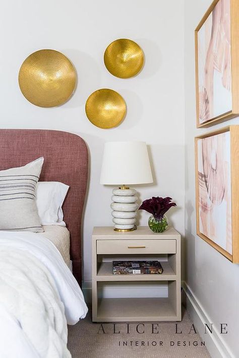 Chic bedroom updated with a mauve headboard and a light taupe nightstand displaying marble rings lamp under hammered brass wall decor. Gray Fabric Headboard, Grey Striped Walls, Brass Wall Decor, Gray Upholstered Headboard, Nailhead Headboard, Alice Lane, Marble Rings, Headboard With Lights, Curved Headboard