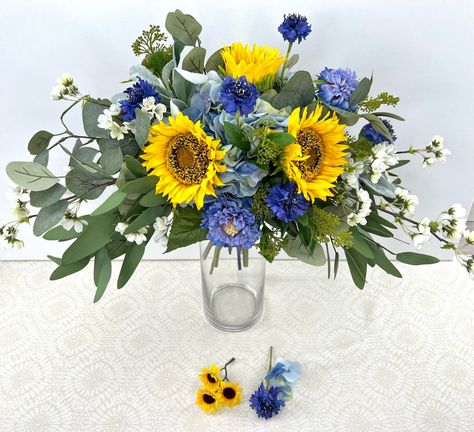 Sunflower and Blue Bridal Bouquet  Dreaming of a romantic outdoor wedding? Take your bridal flowers with you and leave stress behind with a high-end faux flower bouquet.  You will be able to see it before the wedding, enjoy it on the big day, and hold onto it as a keepsake.  ❤️Created in a hand-gathered wide clutch style, this lifelike, Pinterest-worthy Sunflower Bouquet is absolutely stunning!  ❤️The summery palette of yellow and blue is accented with fresh green and loads of texture ❤️ Feature Bridal Bouquet Yellow, Blue Summer Wedding, Bouquet Rustic Wedding, Yellow Bridal Bouquets, Sunflower Bridal Bouquet, White Quince, Faux Flower Bouquets, Bridal Bouquet Blue, Sunflower Arrangements