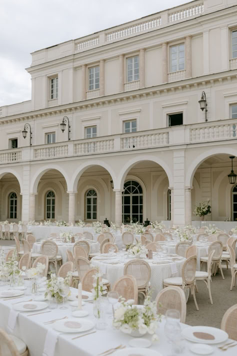 Set in a stunning historic venue, this outdoor wedding reception features beautifully arranged tables with classic cane-back chairs, adorned with elegant white and green floral centerpieces. Perfect for a timeless and sophisticated celebration. #WeddingReception #OutdoorWedding #ElegantDecor #HistoricVenue #FloralCenterpieces #TimelessWedding #SophisticatedCelebration Classic Timeless Wedding Colors, Timeless Wedding Theme Ideas, Wedding Reception Vibes, White And Green Floral Centerpieces, Wedding Reception Classy, Green Floral Centerpieces, Classic Wedding Reception Decor, Elegant Outdoor Wedding Reception, Traditional Wedding Reception