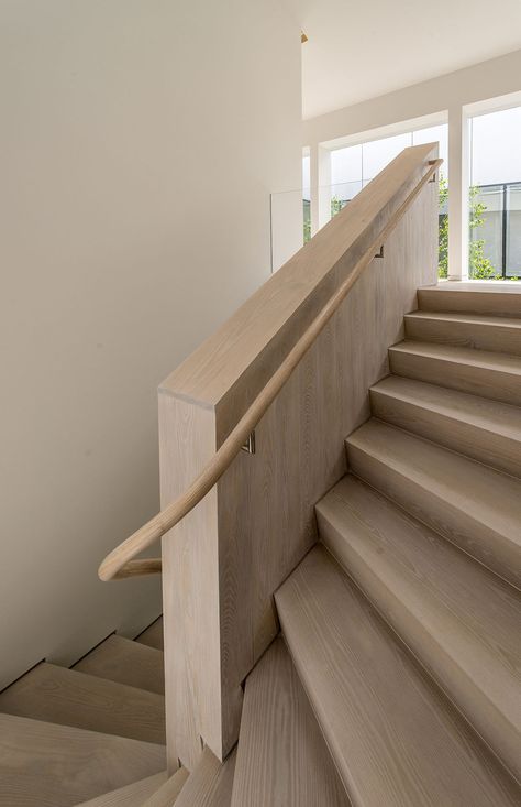 Stained ash winding stair. A continuous reveal on the central wood wall and outer painted wall enhances its presence.  Finishes Walls: Benjamin Moore Decorator White Stair & wall cladding: Stained ash  Products Handrail brackets: Linnea Glass Railing With Wooden Handrail, Timber Handrail Staircase, Wood Stair Handrail, Wall Mounted Handrail Wood, Stair Handrail Detail, Glass Railing Wood Handrail, Decorators White Benjamin Moore, Ash Flooring, Beach Houses Architecture