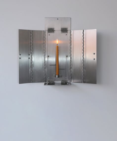 A candle holder rendered in stainless steel is mounted onto the wall as an altar panel painting that folds closed to simulate a medical cabinet. The candle supported by the metal structure is pierced by nails at different heights marking time intervals in a contemporary rendition of the ancient candle alarm clock. Deliberately syncretic, the object references themes of ancient ritual and religious practices while addressing modernist values of asepsis. As the candle shortens the melting wax rele Object References, Wall Mounted Candle Holders, Panel Painting, Medical Cabinet, Vintage Industrial Design, Modern Candle Holders, Wall Candle Holders, Painted Paneling, Wall Candles