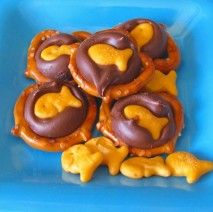 Chocolate, gold fish, and pretzels for a sweet ocean snack.  (I would probably use white chocolate with blue food coloring.) Beach Birthday Party Food Ideas, Fish Snacks For Kids, Fish Themed Food, Ocean Themed Party Food, Fish Dessert, Ocean Snacks, Goldfish Snack, Vbs Snacks, Hersey Kisses