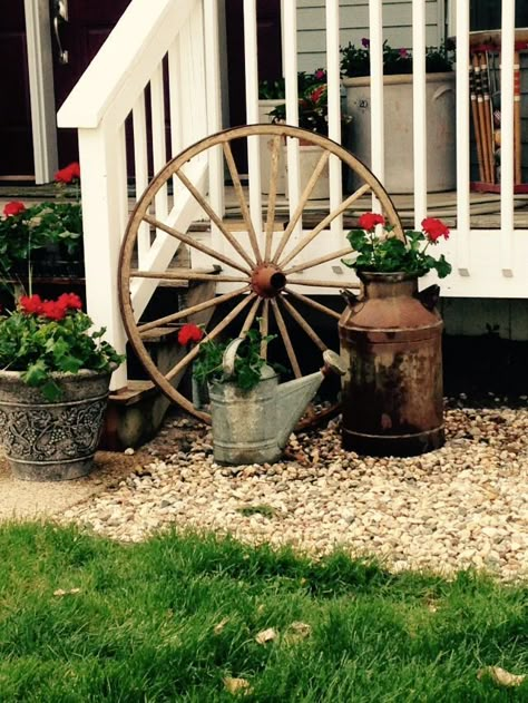 Decorating With Wagon Wheels Front Yards, Old Farmhouse Landscape Ideas, Front Yard Focal Point Landscaping Ideas, Landscaping Farmhouse Front Yard, Milk Can Landscaping Ideas, Country Yard Decor, Rustic Lawn Decor, Country Flower Bed Ideas, Wagon Wheel Landscape Ideas