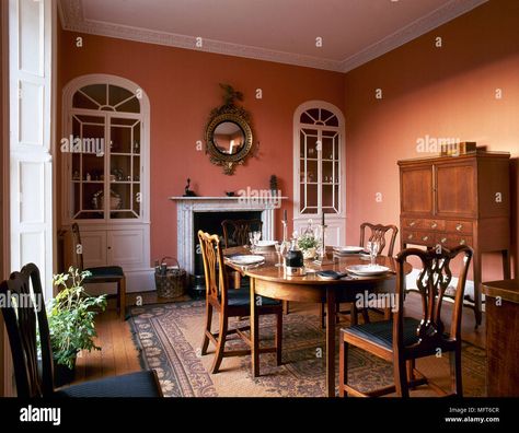 Download this stock image: Traditional dining room with terracotta colour walls, wood side cabinet, oval dining table and chairs, and arched, built-in china cabinets flanking a - MFT6CR from Alamy's library of millions of high resolution stock photos, illustrations and vectors. Terracotta Dining Room, Modern Crockery, Terracotta Walls, Dining Room Colour Schemes, Built In China Cabinet, Crockery Cabinet, Dining Room Paint Colors, Cabinet Designs, English Interior