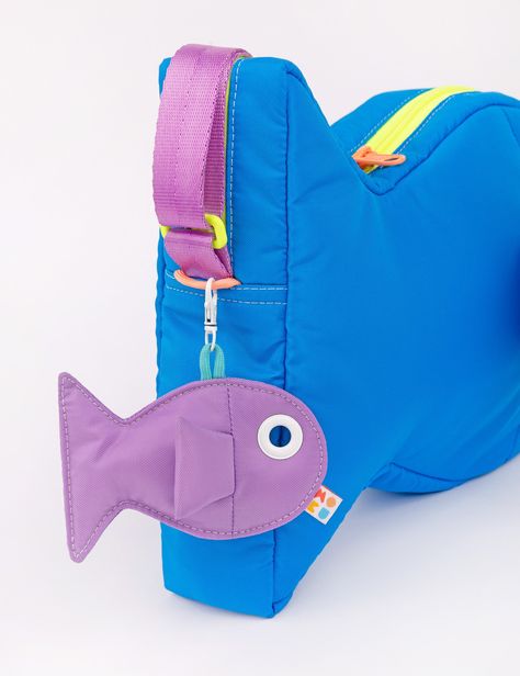 Find a new friend in this super plushy Fish Purse! This bag is so comfy and soft to wear, you'll be making it your daily driver. The inside is super roomy and can fit everything you need. Store small items in the two inside pockets. The grommet eye is the perfect size to thread your phone charger through to keep your phone charged and on hand! Hang your keys or our matching Fish Keychains off the double zipper pulls or the paracord loops on the head & tail of the bag. Adjust the strap to your perfect length- swim along with your shoulder bag or cross body style. Shop The Fish Collection Water resistant 100% nylon fabricFully lined Strap adjusts from 32" to 60" 9.5" tall x 12.5" wide x 2.5" deep, 9 oz. Capacity- 4.8 L Made in Los Angeles, California Keychain Sewing Pattern, Fish Keychains, Fish Purse, Fish Keychain, Fish Bag, Plush Design, Saltwater Fish, Bicycle Bag, Metal Spring