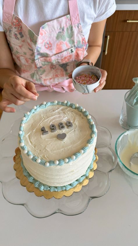 Girl places an edible white pearl sprinkle onto a white cake decorated with blue piping and silver letters that say 1989 Taylor Swift Grocery Store, 1989 Bday Party, 1989 Taylor Swift Party Ideas, Taylor Swift Birthday Cake 1989, Diy Taylor Swift Cake, Easy Taylor Swift Cake, 1989 Taylor Swift Party, 1989 Cake, Eras Tour Cake