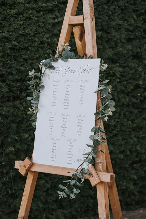 White seating chart on easel and decorated with foliage Country Seating Chart Wedding, Easel Seating Chart, Wedding Seating Chart Easel, Seating Chart Easel, Easel Stand Wedding, Wedding Signage Table, Wooden Seating Chart, White Seating Chart, Wedding Poppy