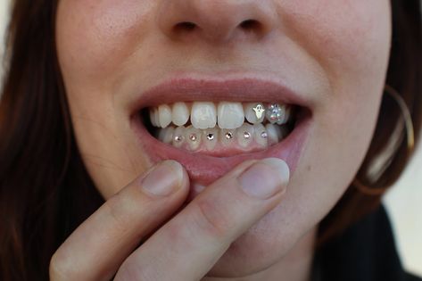 Piercing no dente: item fashionista ou delírio coletivo? Ao que parece, o acessório está de volta com tudo. Se você foi adolescente nos anos 80, 90 ou 2000’s, com certeza foi impactada por essa tendência que brilhava na boca dos jovens daquela época. Não era um piercing de verdade, claro, apenas uma pequena joia ou strass – e que chamava atenção de quem olhava. #piercing | tooth gems | #acessorios | tooth piercing | piercing tooth gems | #toothgems | pedras nos dentes | #piercingnodente Piercing No Dente, Tooth Piercing, Female Accessories, Tooth Gems, Tooth Gem, Teeth Jewelry, Braces, Nose Ring, Gems