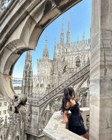 A girl in a black off the shoulder dress, with her long black hair in a half up hairdo, leans on the railing, looking off at the scenery behind her, which showcases the cathedral’s vast detail high in the sky, built of stone in tones of creamy white, sand pink, and streaks of marbled gray. Summer Outfits Milan, Milan Travel Outfits, Milano Outfit Ideas, Milan Spring Outfit, Milan Photoshoot Ideas, Photo Ideas In Italy, Milan Italy Outfit Summer, Milano Outfit Spring, Duomo Di Milano Photo Ideas