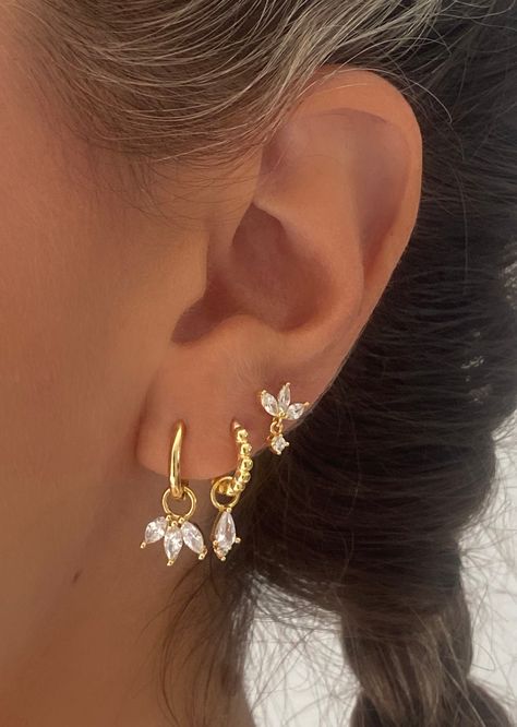 Introducing our exquisite gold-toned marquise earrings—a harmonious blend of classic charm and modern elegance. The earrings feature a delicate petal-like arrangement, reminiscent of a flower or leaf. Pair with Single clear drop earrings and marquise stud earrings for your stunning ear stacks. A. Hannah Dangle• Material: 18k Gold Plated on 925 sterling silver, AAAAA Cubic Zirconia• Size: Charm size: 11mm, Hoop inner diameter: 9mm B. Single Clear • Material: 18k Gold Plated on 925 sterling silver Gold Ear Designs, Gold Earring Inspiration, Gold Formal Earrings, Earring Stack Gold, Gold And Silver Earrings Mixing, Second Ear Piercing Ideas, Stacked Ear Piercings, Earring Stacks Gold, Cute Piercing Ideas