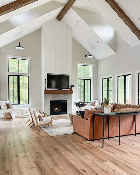 Gray stone tile fireplace with stained wood mantel is built into a floor to ceiling white board and batten wall. A brown leather sofa sits opposite the fireplace in this gray living room with vaulted white shiplap ceilings. Stone Tile Fireplace, Two Story Fireplace, Fireplace Facing, Vaulted Ceiling Living Room, Shiplap Ceiling, Black Interior Doors, White Shiplap Wall, Shiplap Fireplace, Farmhouse Fireplace