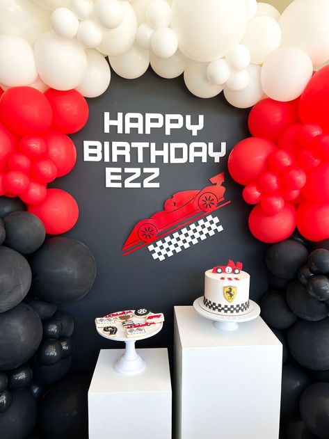 Black wooden backdrop with red, white and black balloon garland. Formula 1 themed signage. Formula 1 cake and sugar cookies. Race car sugar cookies, race car cake, formula 1 kids party ideas, formula 1 backdrop, paradise valley arizona, white cake stands, white pedestals Redbull Racing Birthday Party, Formula 1 Bday Party, Formula One Themed Birthday, F1 Bday Theme, 1st Birthday Party Ideas For Boys Theme Race Cars, Formula 1 Party Theme, Formula 1 1st Birthday, Formula 1 Birthday Cake, F1 First Birthday Party