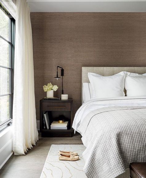 Packed with style, this modern gray and brown bedroom features an accent wall covered in brown grasscloth and positioned behind a heather gray tufted headboard accenting a bed dressed in white and gray bedding complemented with a heather gray waffle blanket. Grey Brown Bedrooms, Grasscloth Wallpaper Bedroom, Brown Bedroom Walls, Grey And Gold Bedroom, Brown Accent Wall, Grey And White Bedding, Beige Headboard, Wallpaper Walls Bedroom, Feature Wall Bedroom