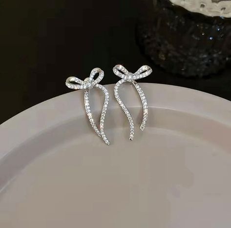 These dangle bow earrings feature a “ribbon” that hangs behind the ear to give a dramatic effect. Hanging Earrings Silver, Bow Earrings Silver, Silver Formal Jewelry, Silver Bow Earrings, Winter Accessories Jewelry, Sparkly Silver Earrings, Ribbon Jewellery, Bow Earring, Ribbon Earrings