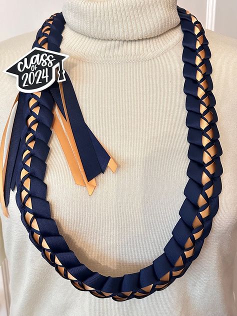 "Celebrate your graduate and give them a souvenir to remember their big accomplishment with this handmade braided lei with 2 colors of ribbon lei.  Select your colors: - 5/8\" grosgrain ribbons on the outside - 3/8\" satin ribbon on the inside see pictures for color reference. For example, first image shows Outside Grosgrain: Navy Blue  Inside Satin: Old Gold Details: - untied measures approximately 40-42\" around - \"class of 2024\" cap is handlettered then cut out of black vinyl and attached to white Cardstock which is glued on to the lei  Check out the other listings in Heart to Heart by Berna for other designs, color combinations, and customized lei options." Graduation Ribbon, Senior Sash, Ribbon Lei, Graduation Leis, Homecoming Mums Diy, Class Of 2025, Heart To Heart, Color Reference, Graduation Diy