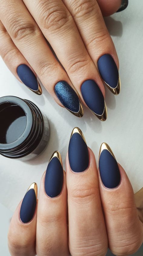 Discover elegance with this exquisite matte navy and gold stiletto nail design! The striking gold tips add a touch of luxury, while the deep navy provides a sophisticated backdrop. Featuring a dazzling blue accent nail, this manicure is perfect for making a bold statement. Try this chic look to elevate your style for any occasion! #NailArt #NailDesign #ChicNails #fallnails #septembernails Navy Blue Nails Matte Art Designs, Sapphire Blue And Gold Nails, Matt Dark Blue Nails, Elegant Blue Nail Designs, Ravenclaw Inspired Nails, Matt Navy Blue Nails, Blue And Gold Chrome Nails, Blue Black And Gold Nails, Navy Blue Wedding Nails Bridesmaids