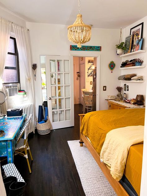 A bedroom with shelves and a desk with floral designs. Small Bedroom With Desk Layout, Dresser In Front Of Window, Desk Next To Bed, Small Bedroom With Desk, Bedroom With Shelves, Hand Painted Desk, Railroad Apartment, Nyc Bedroom, Greenwich Village Apartment