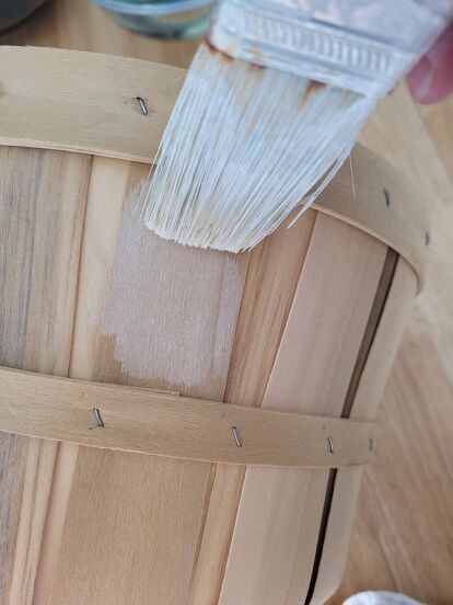 I picked up a few bushel baskets in like new condition from the thrift store. The light, natural wood tone was fine, but I wanted them to fit in better with my cottage farmhouse style. So, I whitewashed them! To make whitewash you'll need white acrylic paint, I like to mix about a tablespoon of white with a drop of antique white. You'll also need a jar or cup for the white wash and a paint brush. Once you add the paint to the jar fill it with water and mix. Saturate your paint b… Porch Mailbox, Bushel Baskets, Apple Baskets, Cheese Box, Washing Basket, Wooden Basket, Whitewash Wood, White Acrylic Paint, White Acrylics