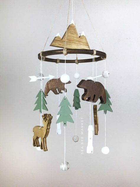 "This woodland crib mobile is one of my favorite designs. The mobile has everything to perfectly tie together a woodland, lumberjack, or camping themed nursery. The mobile comes complete with a snow capped mountain, two bears, two deers, four pointy trees, four modern arrows, four heather grey wool balls and four white wool balls. The colors perfectly contrast each other and are warm and inviting! The hanger is jute twine to tie together the perfect woodland look. Each piece is carved, hand sand Mountain Outdoor Theme Nursery, Tree Theme Nursery, Park Ranger Nursery, Cabin Nursery Theme, Mountain Baby Nursery, Camping Themed Nursery, Adventure Nursery Theme, Outdoor Themed Nursery, Camping Theme Bedroom