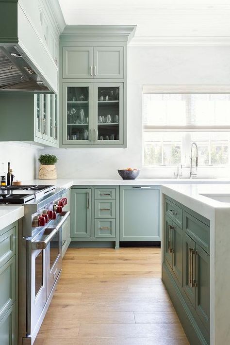 Kitchen features sage green kitchen island honed with white marble waterfall countertop and sage green cabinets with brass pulls. Green Kitchen Island, Kitchen Cabinet Inspiration, Green Kitchen Designs, Cabinet Inspiration, Sage Green Kitchen, Dark Countertops, Green Kitchen Cabinets, Glass Front Cabinets, Green Paint Colors