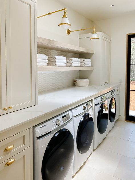 All the function in this laundry room. Double washer and dryer, ample folding space, and a thoughtful mix of enclosed and open storage. Add some gorgeous hardware and an interesting light fixture to elevate your utility space. Laundry room, Samsung washer, Samsung dryer, towels, bathroom towels, cabinet hardware, laundry room paint, greige paint, tile backsplash, basket, laundry room basket, lighting, laundry room lighting, pendant lighting. Follow my shop @Thedendesigngroup on the @shop.LTK app to shop this post and get my exclusive app-only content! #liketkit #LTKstyletip #LTKhome @shop.ltk https://liketk.it/4vo9Y Two Washers And Dryers, Laundry Room Baskets, Den Design, Laundry Room Paint, Washers And Dryers, Custom Laundry Room, Laundry Room Lighting, White Floating Shelves, Laundry Room Remodel