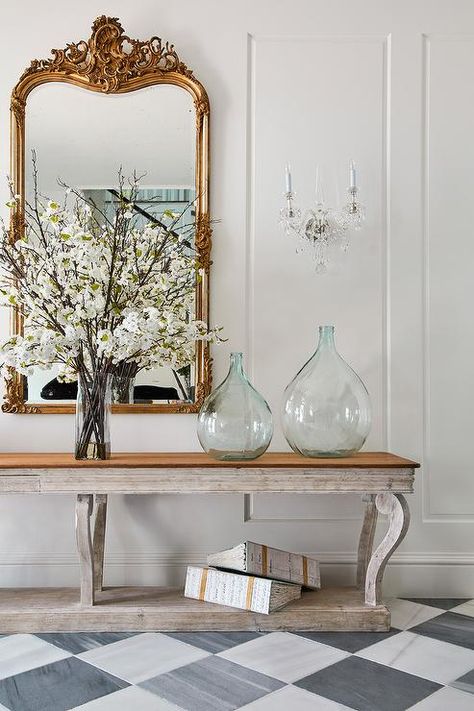 French foyer showcasing a gray wooden French console table with a gilt mirror and lovely recycled glass jugs atop white and gray harlequin floor tiles. French Foyer, French Console Table, Wood Floor Finishes, White Leather Dining Chairs, Grey Wood Floors, Herringbone Wood Floor, Console Table Styling, Wood Armoire, Oak Wood Floors