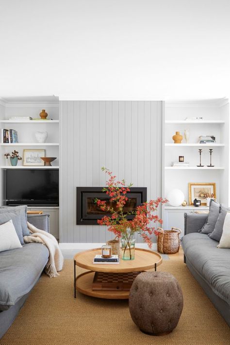 VJ panelling on the fireplace is flanked by open shelving on either side of this neutral living room, with a pair of soft grey sofas drawn up to a round coffee table with a storage tray underneath. Grey Vj Panelling Living Room, Living Room Vj Panelling, Vj Panelling Fireplace Wall, Vj Fireplace, Vj Panelling Lounge Room, Vj Panelling Fireplace, Vj Panelling Living Room, Vj Panelling, Hampton Living Room