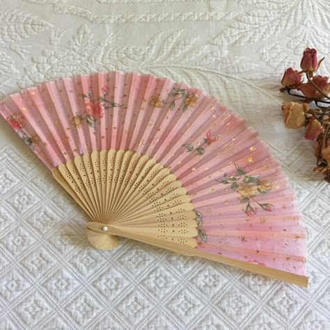 Vintage Silk and Wood Hand Fan. Openwork Design on Wood with Floral Designs and Metallic Gold Stars on the Fabric. Lovely Fan. This fan is new, never used and in good shape. Use for Costuming or for any day. Size: 14 3/8" Open, 8 1/4" Long Fan Blades, 3/8" At Top of each fan stick blade.  For other vintage, antique, and handmade items see: www.VeryVictorianStudio.etsy.com. For sewing related items see my other shop: www.SewingRoomStore.etsy.com. Thank you for looking! Hand Fan Aesthetic, Bridgerton Cookies, Regency Fan, Fun Halloween Outfits, Fan Aesthetic, Fan Hand, Pink Items, Antique Fans, Vintage Fan