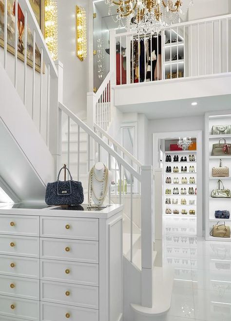 Glamorous 2 story custom closet boasts a tall white jewelry dresser accented with gold knobs and a glass top and placed against an all white staircase. Two Story Closet, 2 Story Closet, Transitional Closet, Master Closets, House Of Pain, Luxury Closets, Closets Design, White Staircase, Dressing Room Closet