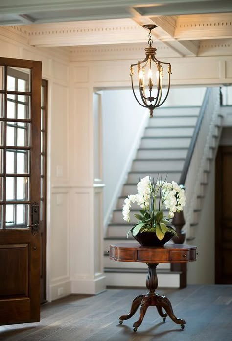 Dark stained double doors open to an absolutely gorgeous foyer featuring a coffered ceiling accented with an antique brass lantern hanging over a round antique table topped with orchids. Round Foyer, Round Foyer Table, Traditional Foyer, Foyer Lighting Fixtures, Foyer Table, Foyer Decor, Foyer Lighting, Traditional Interior Design, Foyer Decorating