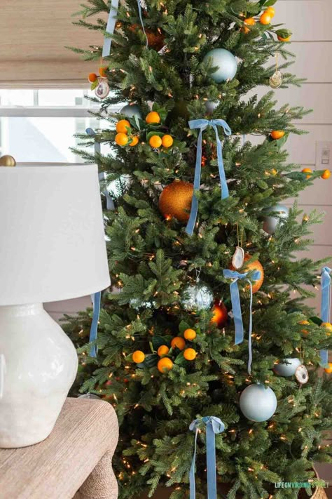 A coastal Christmas tree decorated with orange stems, light blue orb ornaments, large orange ornaments, oyster shell ornaments, and light blue velvet ribbon bows! Orange And Blue Christmas, The Happiest Season, Orange Christmas Tree, Happiest Season, Coastal Christmas Tree, Christmas Tree Inspo, Chinoiserie Christmas, Blue Christmas Decor, Coastal Christmas Decor