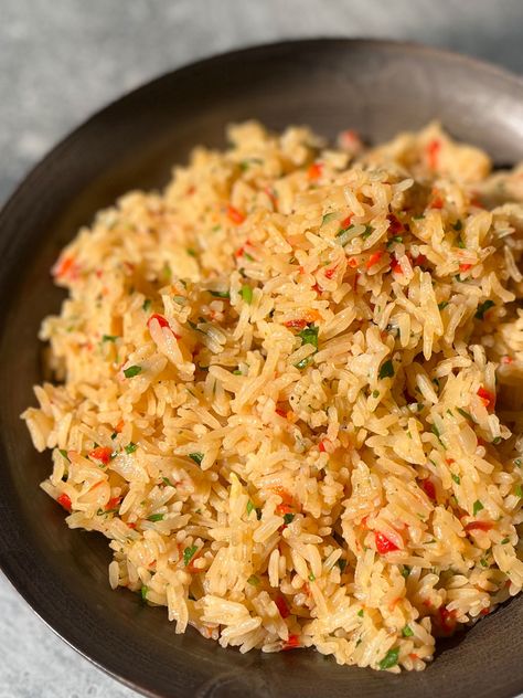 There is a brown bowl with cooked rice, chopped onion, chopped red pepper, chopped fresh parsley, and minced garlic in it. The bowl is on a light gray surface. Rice Peppers And Onions, Beefy Onion Rice, Rice With Peppers And Onions Side Dish, Yellow Rice With Peppers And Onions, Garlic Rice Pilaf, Chile Relleno Casserole Recipe, Onion Rice, Seasoned Rice Recipes, Bowl Of Rice