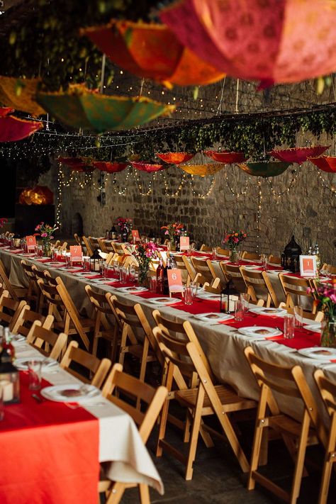 Banquet tables complete with white tablecloth and colourful table runners as Indian umbrellas hang above finished with fairy lights Indian Banquet, Umbrella Wedding Decorations, Colorful Tablescapes, Eating Table, Long Table Wedding, Barn Wedding Photography, Umbrella Decorations, Wedding Table Names, Umbrella Wedding