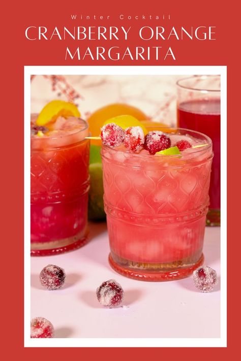 Glass filled with a cranberry orange margarita with sugared cranberries and lime slices as the garnish. Cranberry Orange Margarita Sangria, Easy Holiday Margarita, Frozen Cranberry Margarita Recipe, Pitcher Cranberry Margaritas, Cranberry Margaritas For A Crowd, Orange Cranberry Drink, Cranberry Orange Juice Cocktail, Spiced Cranberry Margarita, Cranberry Pomegranate Margarita