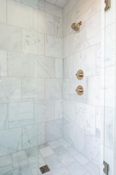 Large square marble wall tiles in a transitional shower delivers a timeless appeal fitted with a brushed gold shower kit and a seamless glass enclosed door. Faux Marble Shower Tile, Square Marble Tile Bathroom, Small Marble Shower Room, Shower With Square Tile, Large Square Shower Tile, Square Tile Shower Wall, 12x12 Tile Shower Wall, Square Shower Tile, 12 X 24 Tile Bathroom Shower Walls