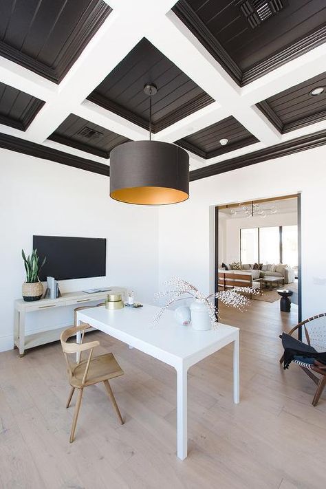 A white and black coffered ceiling holds a black drum hanging shade over a white desk matched with a wooden desk chair. Black Coffered Ceiling, Study Lighting, Wooden Desk Chairs, Office Ceiling, White Beams, Custom Barn Doors, Home Goods Store, White Desk, Black Ceiling