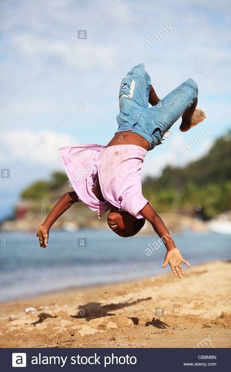 A boy in mid air does a back flip somersault at the beach in Stock Photo - Alamy Mid Air Pose, Back Flip Pose Reference, Hanging From Tree Pose, Surfing Pose Reference Drawing, Holding Surfboard Pose, People Jumping Off Cliffs, Surfer Sitting On Board, Pose Reference, Stock Photography