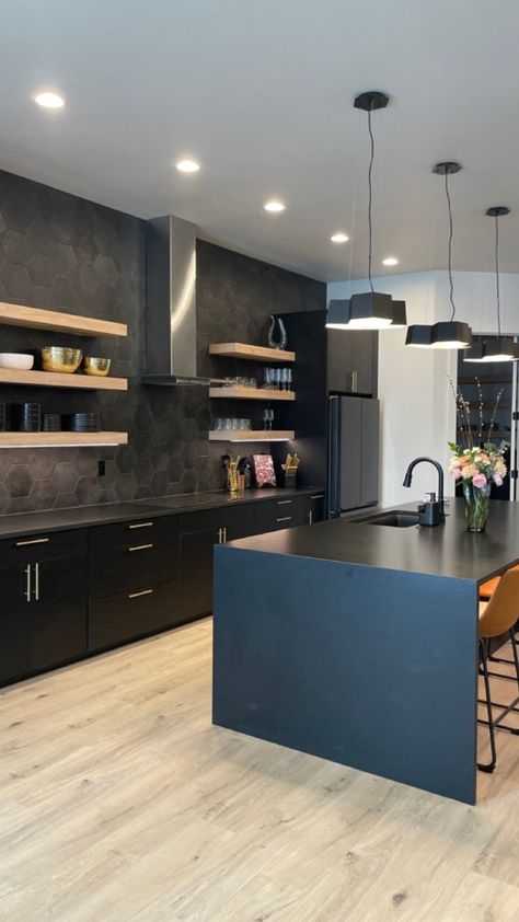 A functional design but with a modern feel in this open concept kitchen. The light and dark contrasts gives this space a bold look, especially the black hexagon tiles for texture against the light tan floating shelves. The black waterfall island gives a clean edge with great space to entertain. Hexagon Shelves In Kitchen, Black Waterfall Island, Luxury Modern Kitchen Design, Waterfall Island Kitchen, Black Hexagon Tile, Black Modern Kitchen, Luxury Modern Kitchen, Kitchen Floating Shelves, Waterfall Island