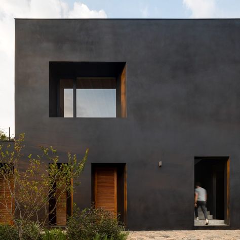 A matte-black rendering called Corev Mooth covers the walls of this residence, while window frames and shutters are made from a tropical tzalam wood coated in reddish sealer as a contrast.  Called Las Golondrinas, the house is composed of three volumes topped by a large sloped roof to create a covered patio that opens onto a swimming pool that aligns with the tree canopy. Matte Black House, Stone Deck, Basement Floor Plans, Weekend House, Black House Exterior, Good House, Black Exterior, City House, Black Walls