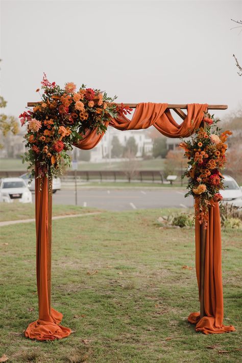 Saffron Wedding Theme, Burnt Orange Wedding Flower Girl, Wedding Arch Burnt Orange, Outdoor Wedding Fall Ideas, Fall Themed Wedding Arch, Terracotta Wedding Arch Decor, Black Gold And Terracotta Wedding, Dark Red And Burnt Orange Wedding, Cozy Fall Wedding Decor