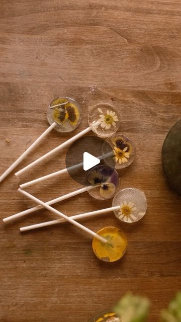 Sibia Torres Padilla | DIYs on Instagram: "This is a simple way to make DIY edible flower lollipops without any candy making experience, just a few minutes and supplies 
Danny said “wow I like pollen, I can see why the bees love it”

In a lollipop mold we added edible flowers like
• pansies
• chamomile
• lavender pods
• calendula petals
We inserted the lollipop stick over the flowers
Added two hard candies over them (my kids actually really like these crystal mint candy which is why we had them on hand)
Bake at 250° F until the candy melts ( the time will depend. 4 lollipops took 14 minutes but the more you bake at once the longer they will take)
Remove from the oven and allow to cool completely before popping them out of the mold
Eat!
These were fun to make and I think they make a really Cottage Core Food, Flower Lollipops, Hard Candy Lollipops, Diy Edible, Lollipop Mould, Candy Factory, Lollipop Sticks, Mint Candy, Candy Making