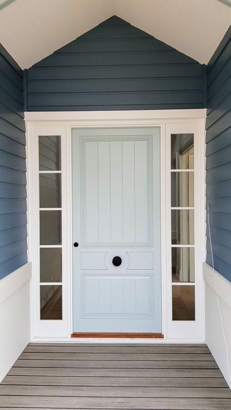 This lovely solid timber entrance door has a unique design with tongue-and-groove panels and a central panel with a fluted round handle. Cedar West also supplied the timber frame and sidelite windows, which have been painted white to contrast with the colour of the door. Find out more about our custom door designs here: https://cedarwest.com.au/custom-door-designs Coastal Front Doors, Hamptons Front Door, Coastal Facade, House Frontage, Timber Entrance, Country Front Door, Timber Sliding Doors, Cedar Door, Stacker Doors